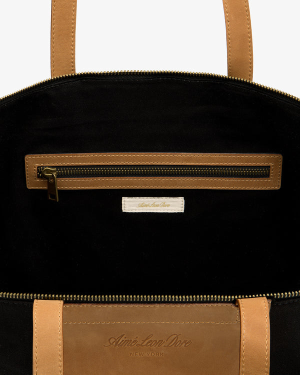 Close-up of Leather Canvas Zip Tote’s tan interior with zip pocket and Aimé Leon Dore label.