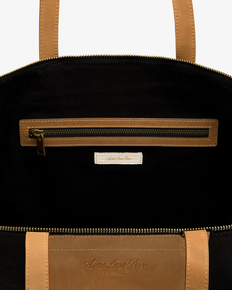 Close-up of Leather Canvas Zip Tote’s tan interior with zip pocket and Aimé Leon Dore label.