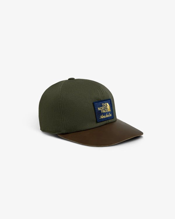 ALD / The North Face Leather Brim Logo Hat, green with brown brim and blue/yellow patch, shown on white background.