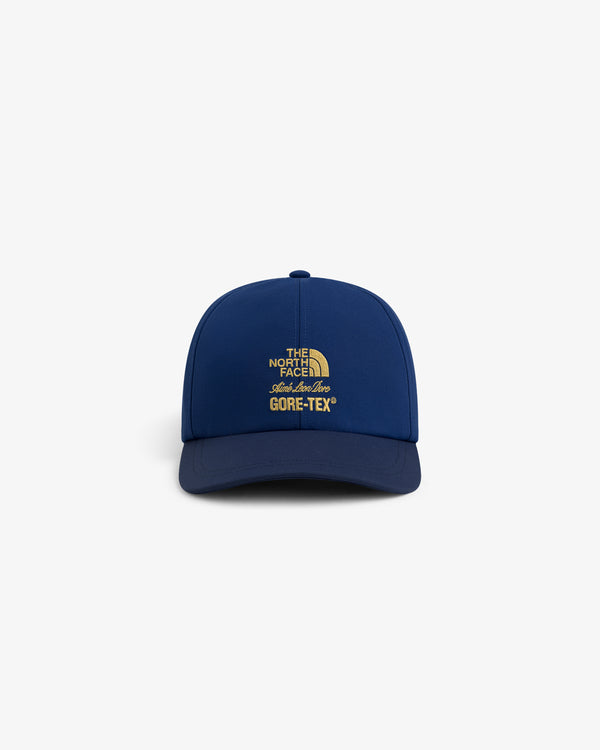 Front view of blue ALD / The North Face GORE-TEX Hat with yellow logo on plain white background.