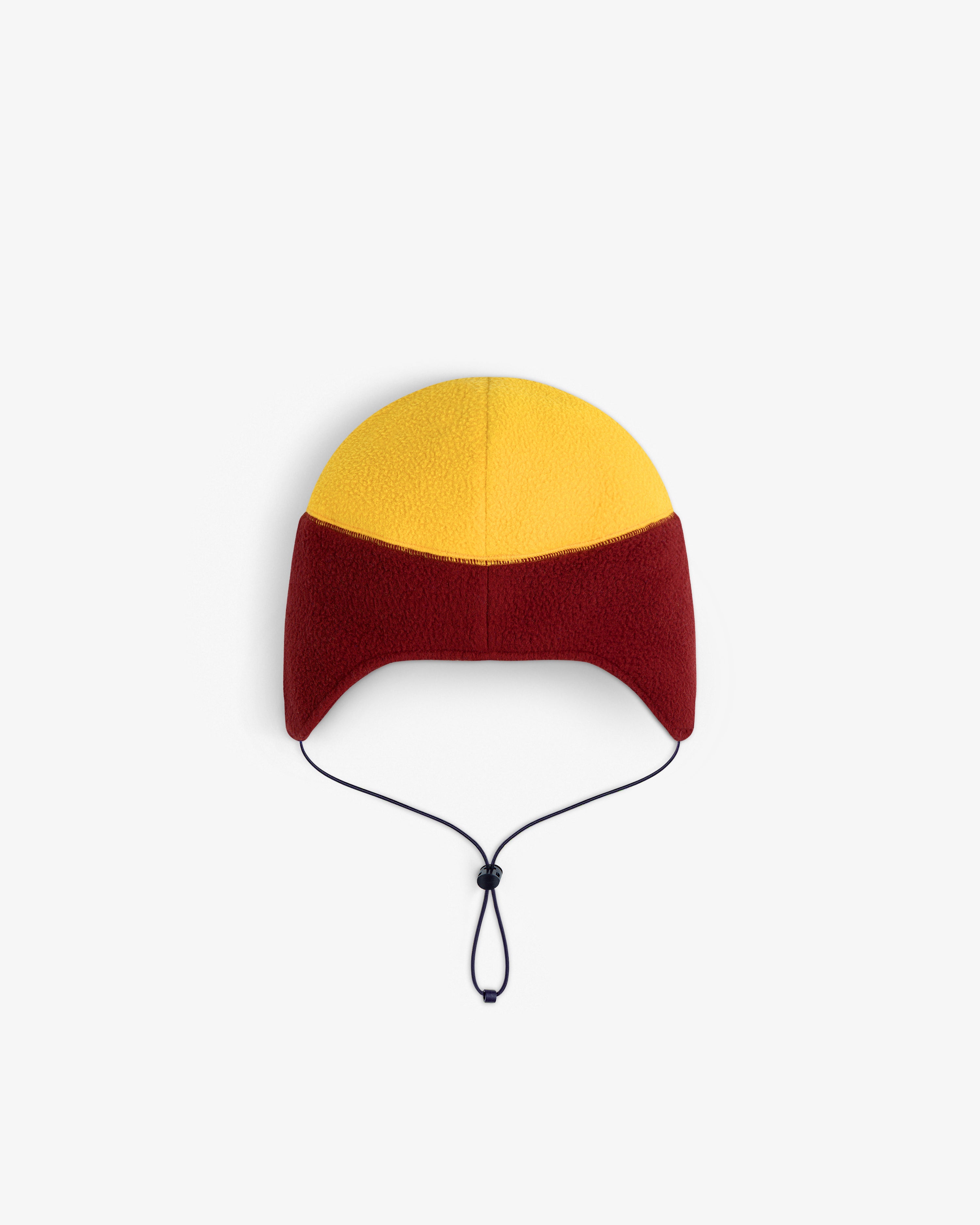 ALD / The North Face Fleece Earflap Hat with yellow crown, red sides, ear flaps, and black adjustable chin cord.