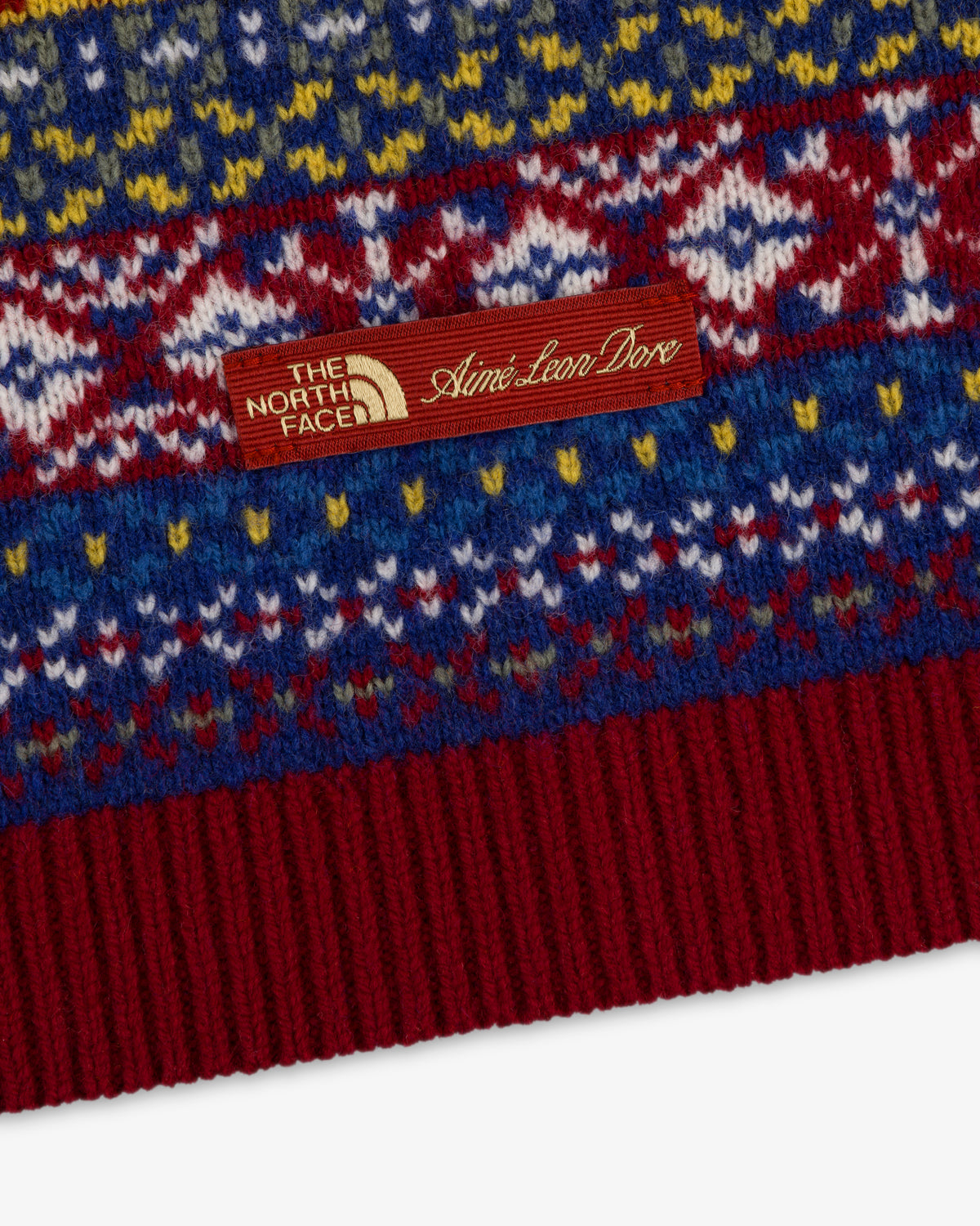 Close-up of the ALD / The North Face Fair Isle Balaclava with a brown dual-branded tag sewn onto the knit fabric.