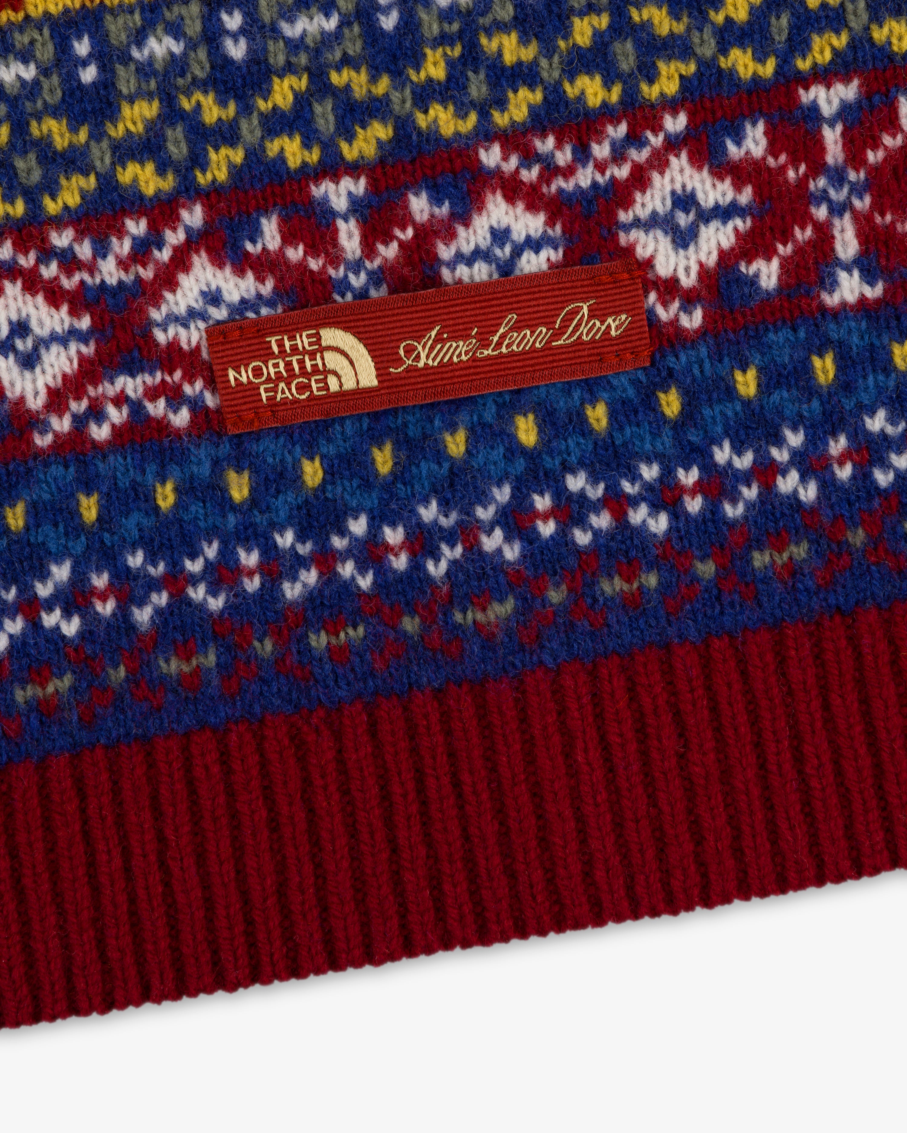 Close-up of the ALD / The North Face Fair Isle Balaclava with a brown dual-branded tag sewn onto the knit fabric.