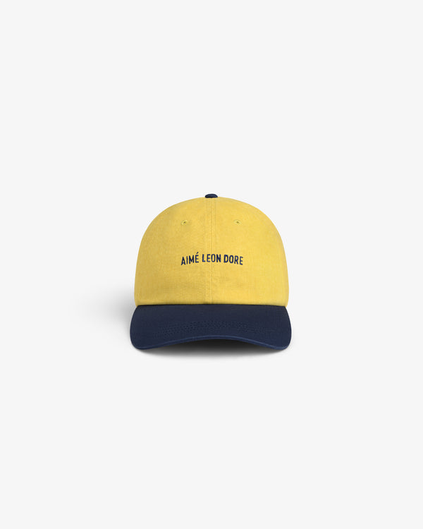 Pigment Dyed Logo Hat in yellow with navy brim, AIMÉ LEON DORE text on front.