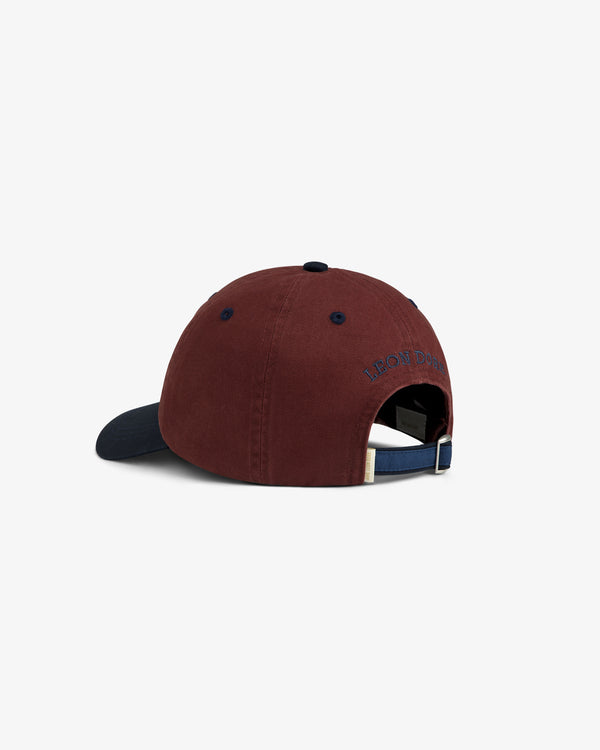 Crest Shield Hat—maroon with navy brim, adjustable back strap, small blue text shown from the rear view.