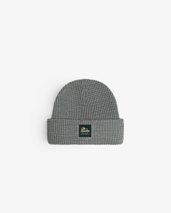 Waffle Knit Beanie in gray with folded brim and black patch, shown on a white background.