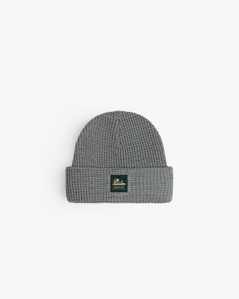 Waffle Knit Beanie in gray with folded brim and black patch, shown on a white background.