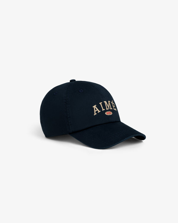 Aimé Souvenir Hat: Navy cap with “AIMÉ” in beige embroidery on front, shown against a white background.