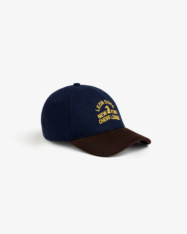 Navy blue Triborough Chess Club Wool Hat with brown brim and yellow “LEON DORE NEW YORK CHESS LEAGUE” embroidery.