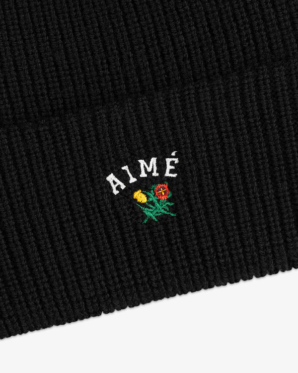 Crest Merino Wool Beanie in black with AIMÉ and embroidered yellow and red flowers below the text.