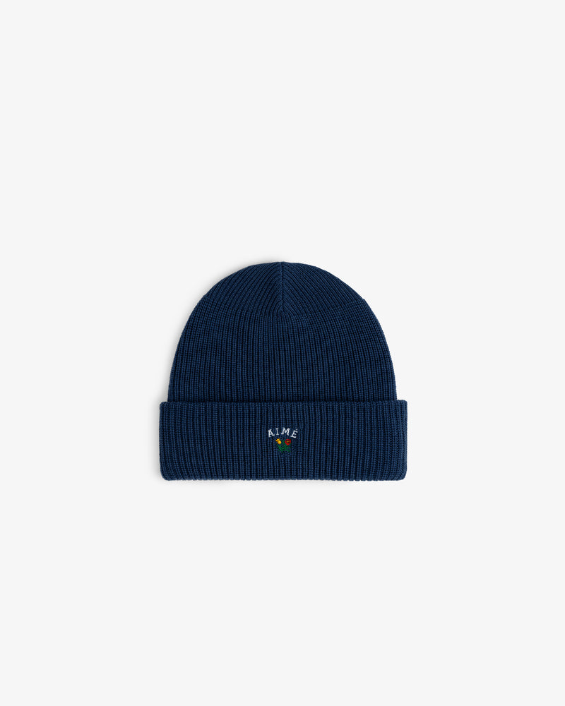 Crest Merino Wool Beanie: navy blue ribbed knit with folded cuff and small colorful embroidered front text.