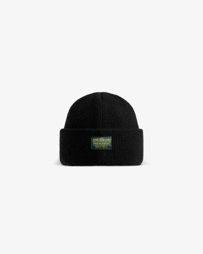 Wool Brim Beanie: a black knit beanie with a folded cuff and a green rectangular patch featuring yellow text.