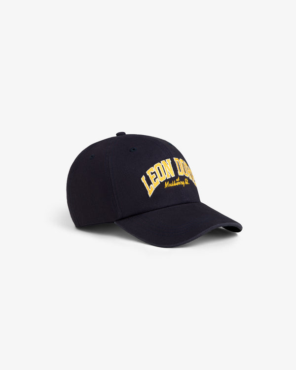 This is the Mulberry Letterman Hat, a navy blue cap with yellow “LEON DORE Midtown, NY” embroidered on the front.