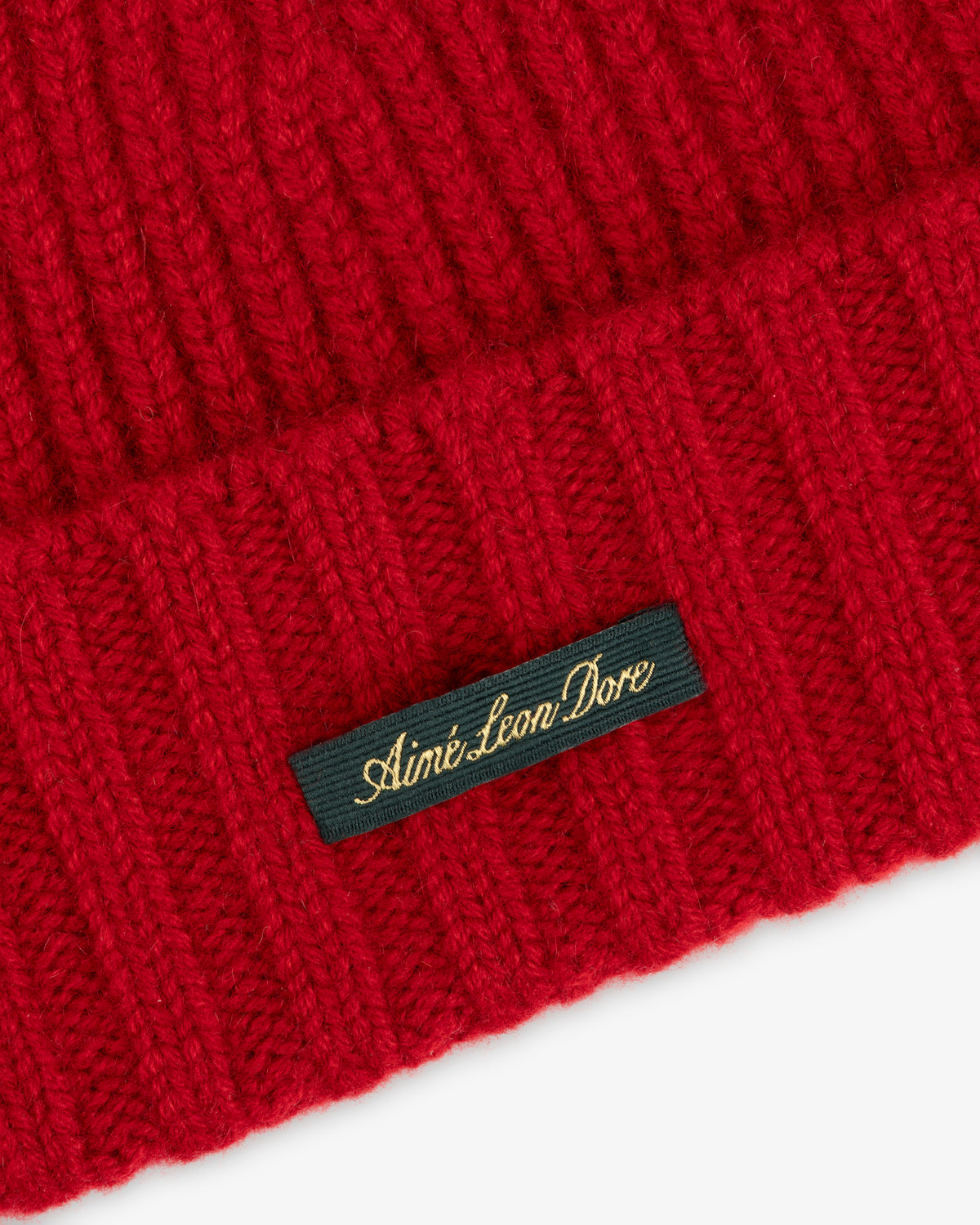 Red ribbed-knit Cashmere Beanie featuring a black woven label with gold cursive text reading Aimé Leon Dore.