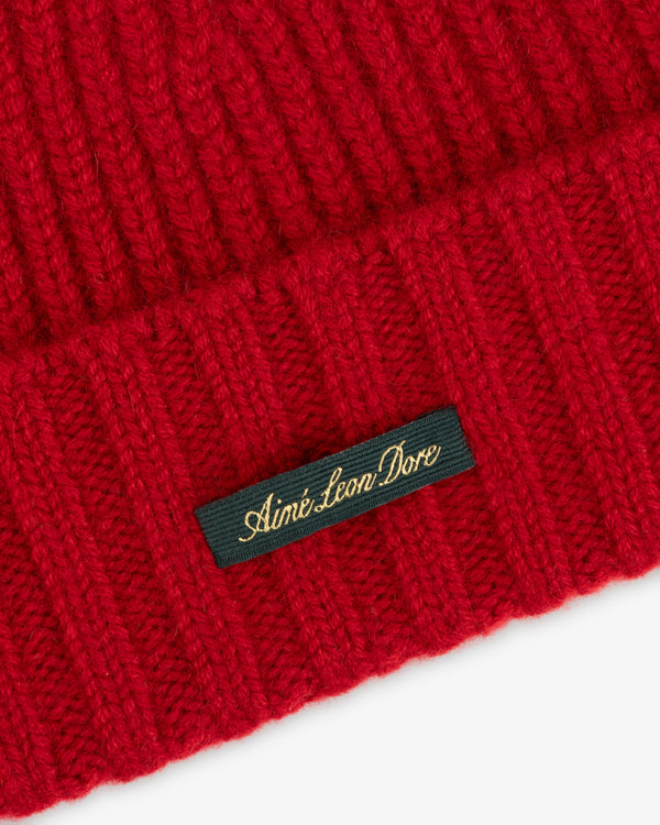 Red ribbed-knit Cashmere Beanie featuring a black woven label with gold cursive text reading Aimé Leon Dore.