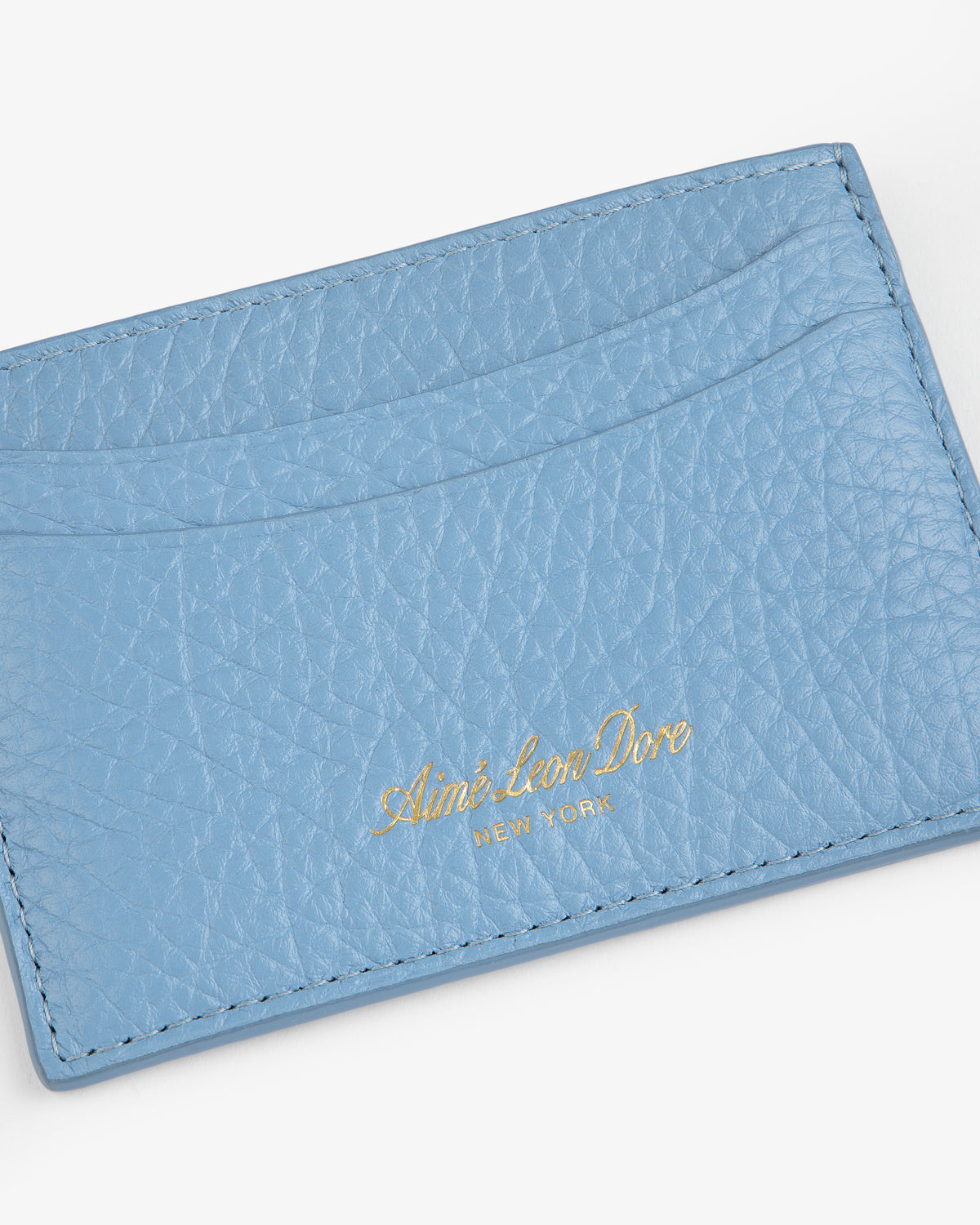 Light blue Tumbled Leather Card Holder with Aimé Leon Dore New York in gold text on the front.