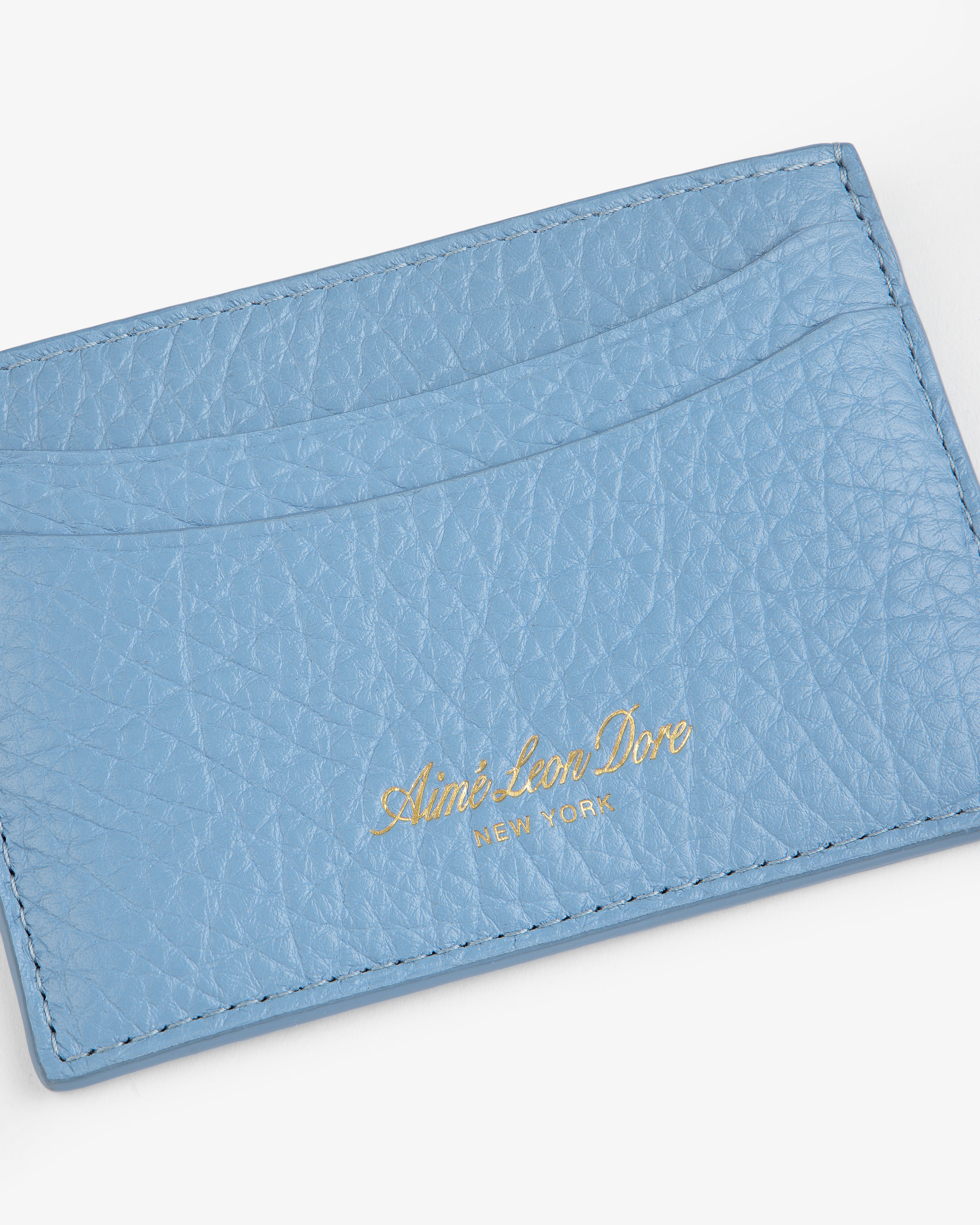 Light blue Tumbled Leather Card Holder with Aimé Leon Dore New York in gold text on the front.