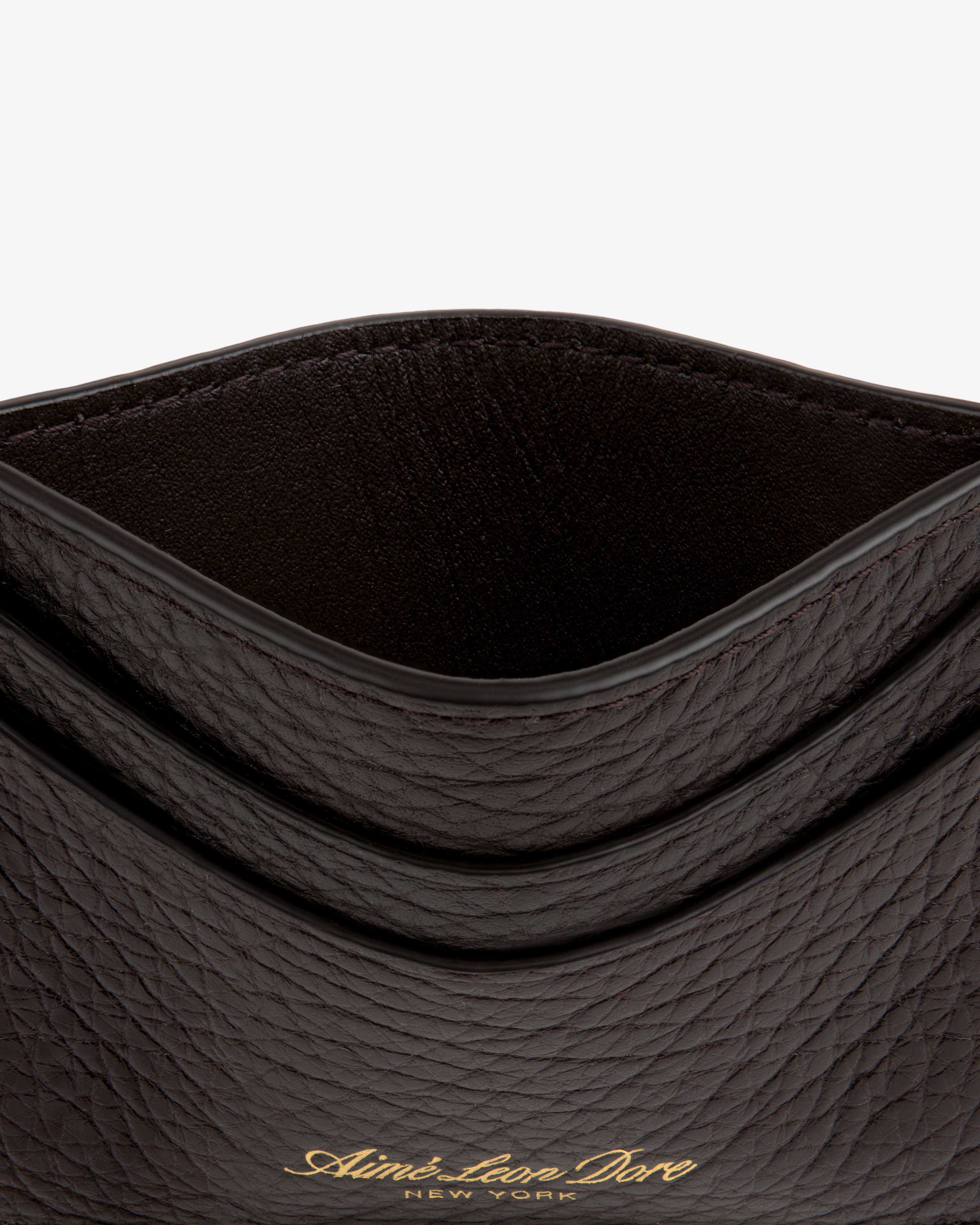 Close-up of an open Tumbled Leather Card Holder in textured dark brown with gold Aimé Leon Dore New York text on front.
