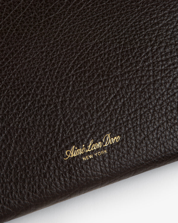 Close-up of Small Tumbled Leather Pouch’s black textured leather, embossed with gold Aimé Leon Dore NEW YORK.