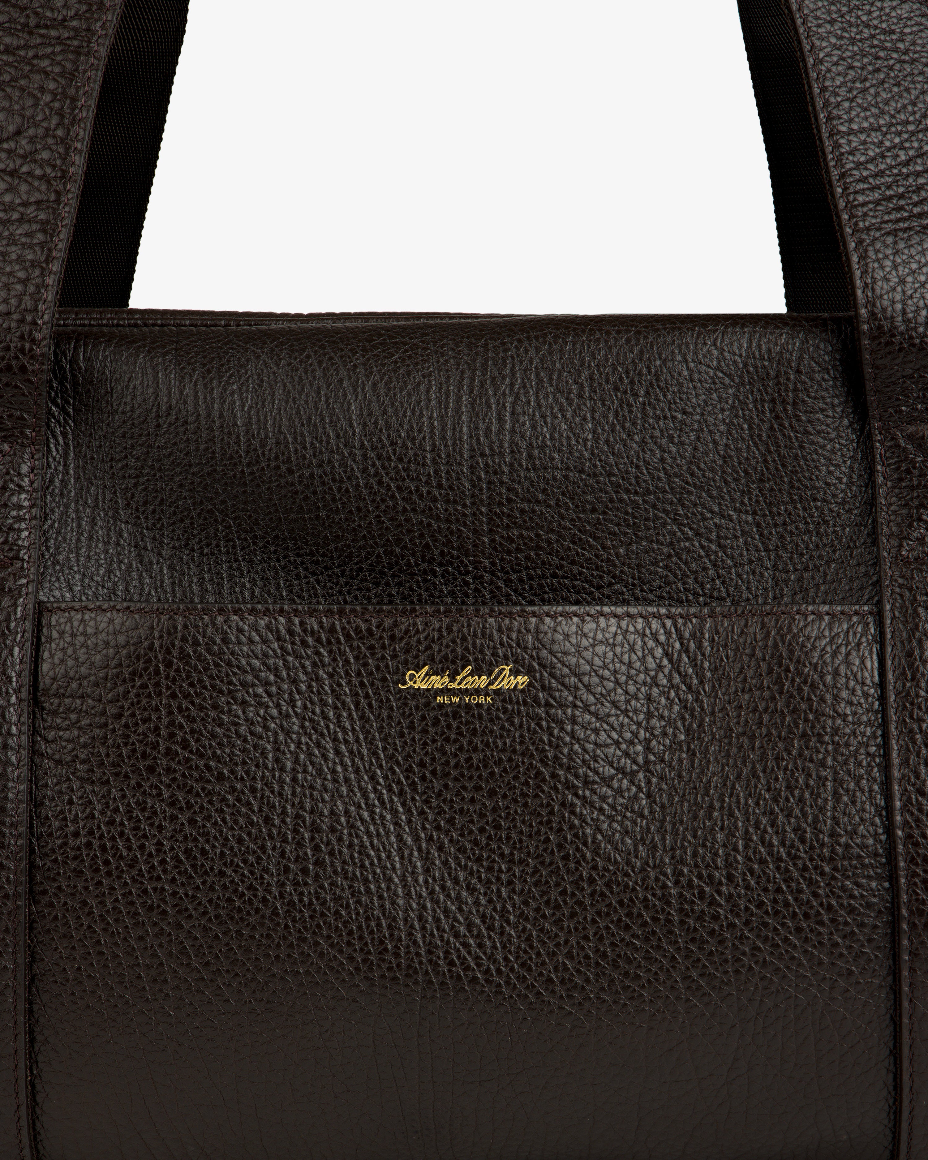 Close-up of the Tumbled Leather Duffle in dark brown with gold Aimé Leon Dore NEW YORK logo on the front.