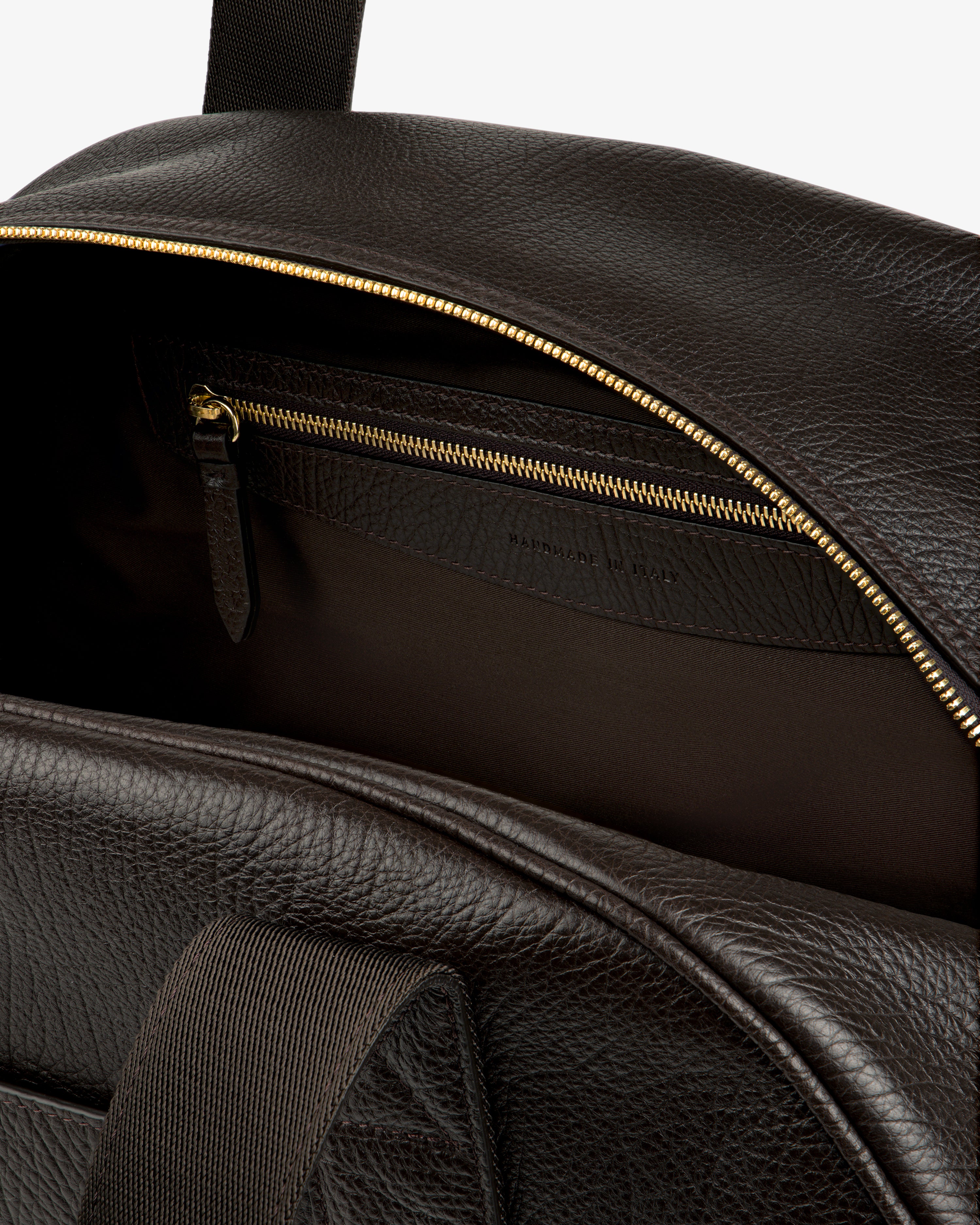 Tumbled Leather Duffle in brown, open to show gold zipper, inner pocket, and “Handmade in Italy” inside.