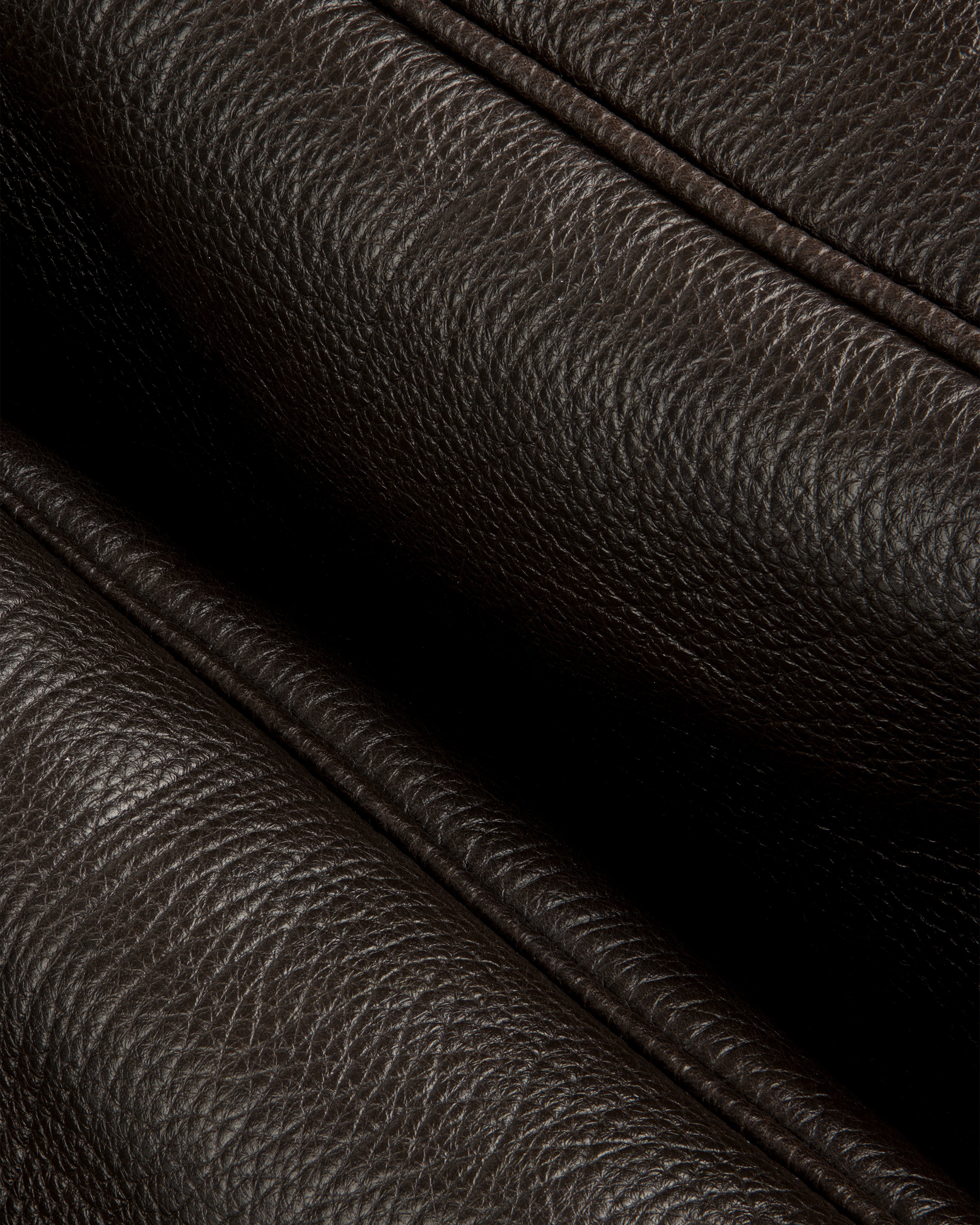 Close-up of Tumbled Leather Duffle’s dark brown textured leather with visible grain and stitched folded edges.