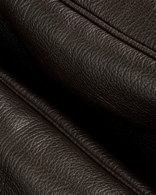 Close-up of Tumbled Leather Duffle’s dark brown textured leather with visible grain and stitched folded edges.