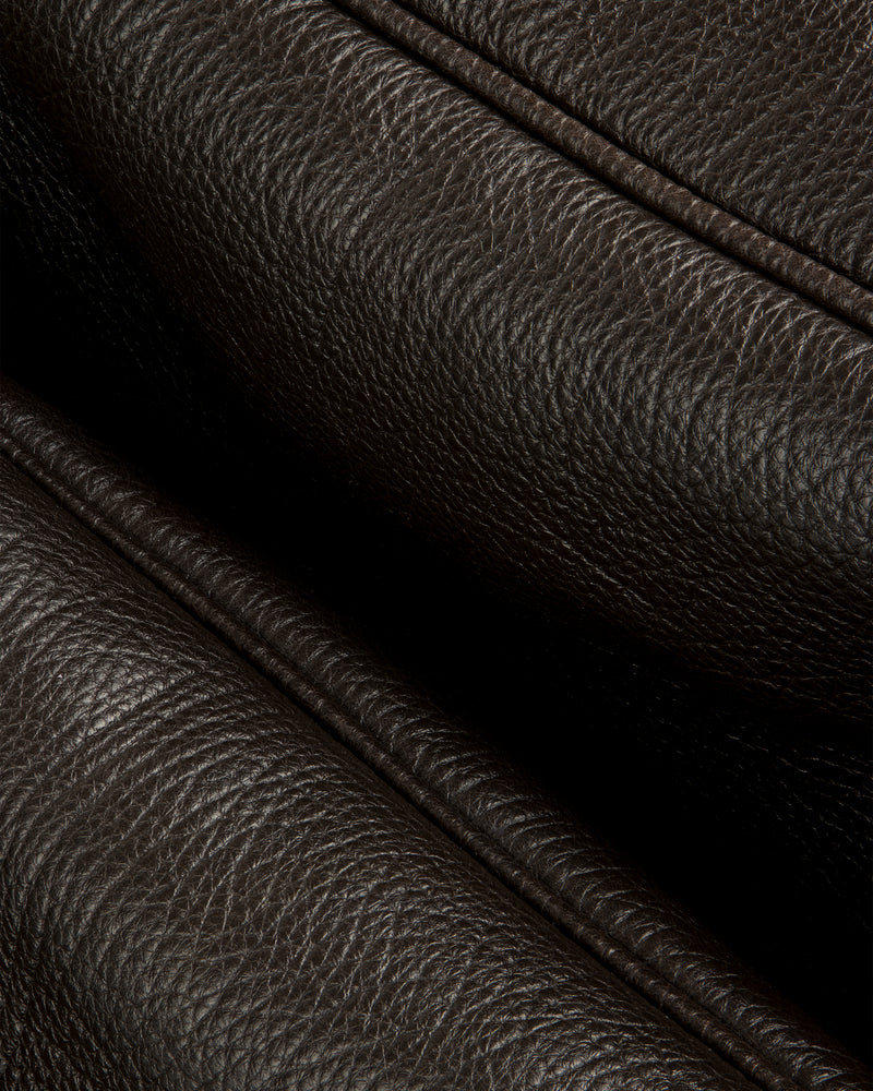 Close-up of Tumbled Leather Duffle’s dark brown textured leather with visible grain and stitched folded edges.