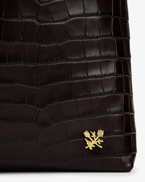 Croc-Embossed Leather Shoulder Bag in dark brown with a crocodile-embossed texture and a gold flower emblem.