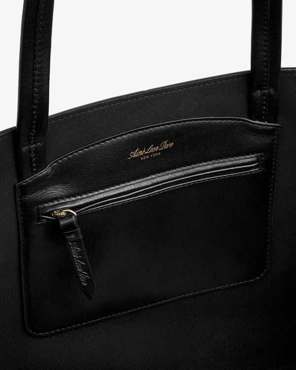 Interior of a black leather Napa Leather Shoulder Bag with a zippered pocket featuring gold lettering.