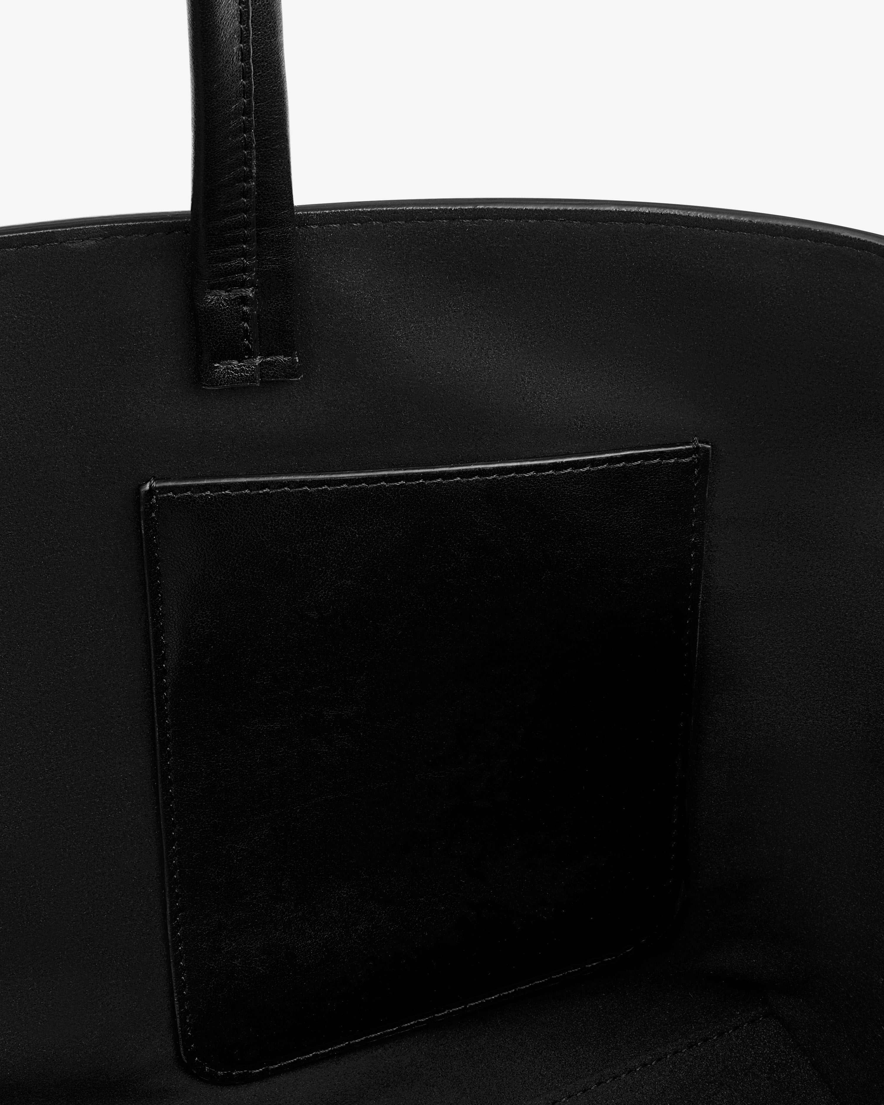 Interior view of the black Napa Leather Shoulder Bag, showing a flat pocket and a strap attachment.