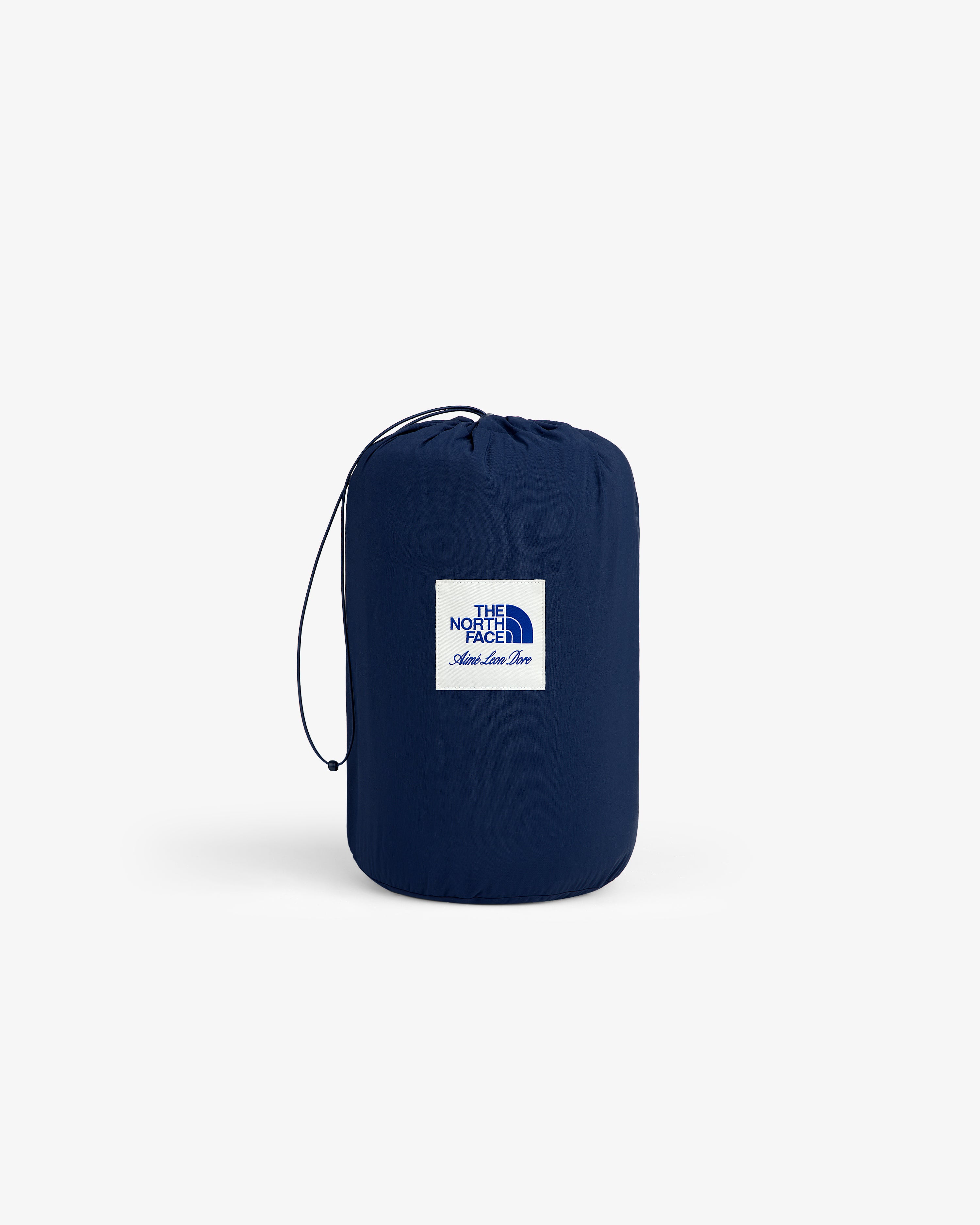A navy ALD/The North Face packable fleece blanket with white logo patch, drawstring, and simple background.