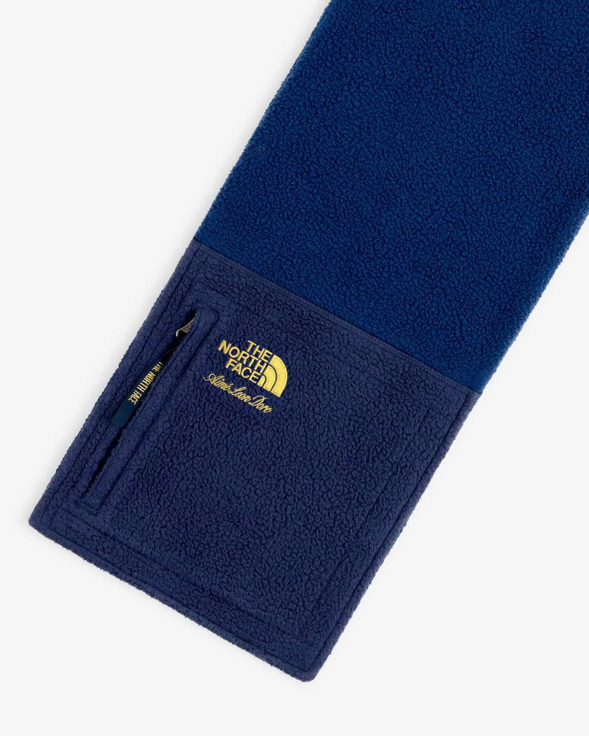 ALD / The North Face Denali Fleece Scarf in blue with a zippered pocket and yellow embroidered logo on one end.
