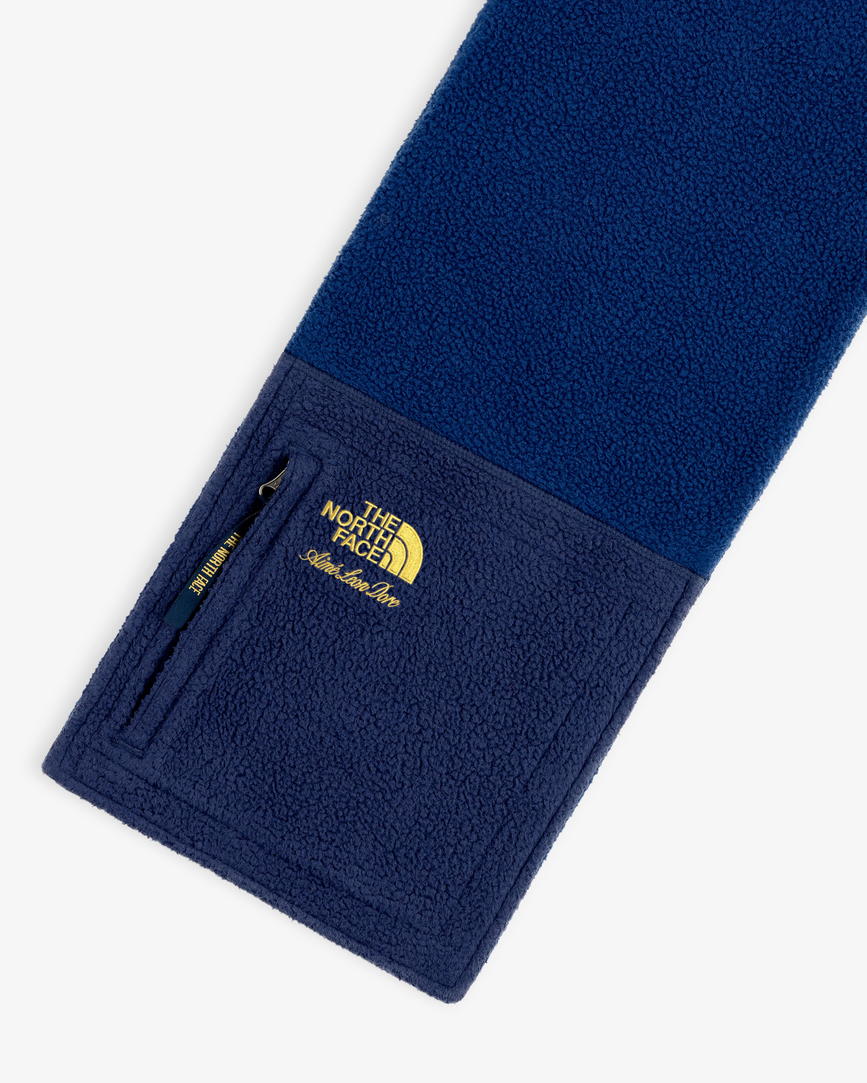 ALD / The North Face Denali Fleece Scarf in blue with a zippered pocket and yellow embroidered logo on one end.
