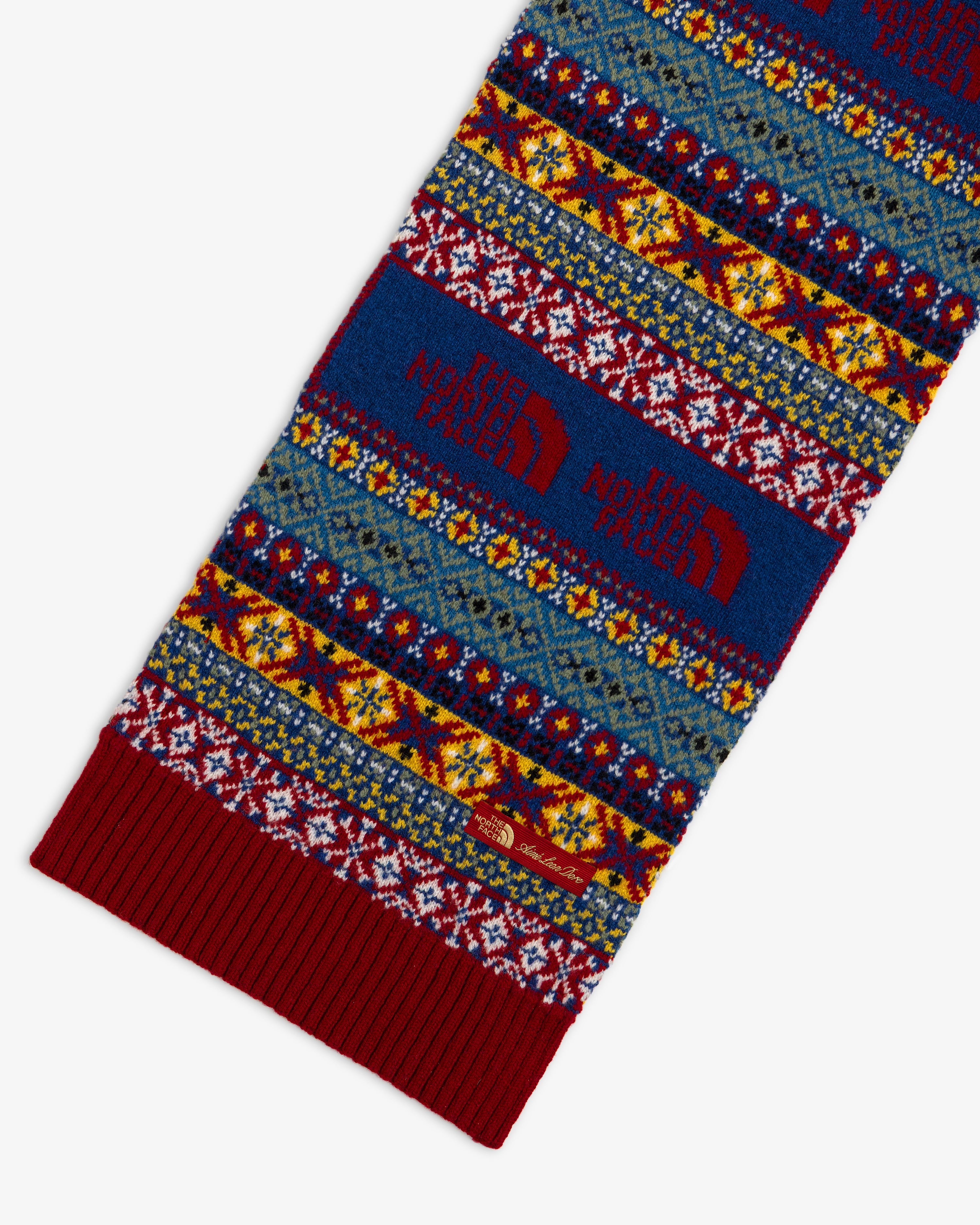 ALD / The North Face Fair Isle Scarf featuring a multicolored pattern, large red brand logos, and a ribbed edge.