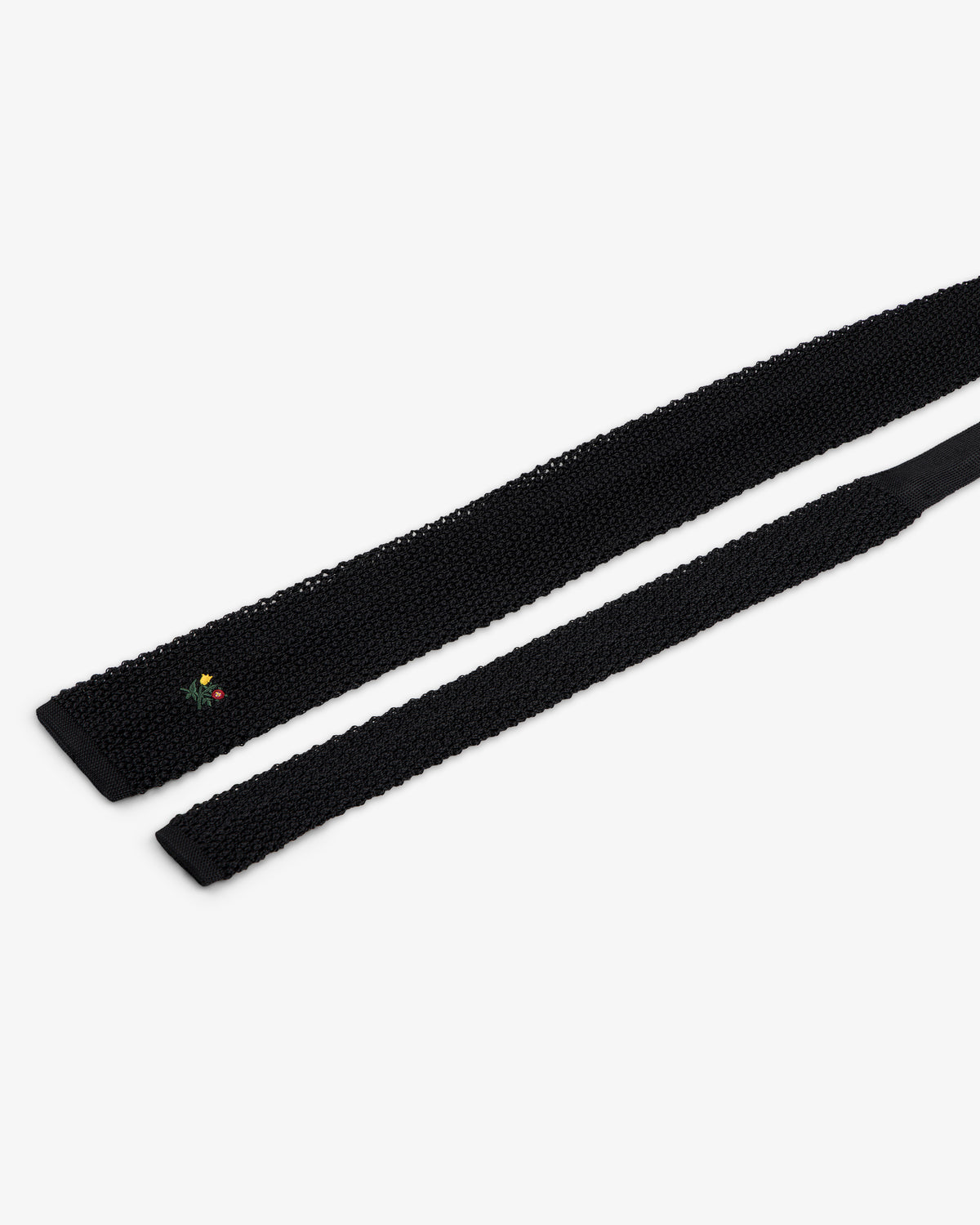 Crest Silk Knit Tie in black with small floral embroidery near the tip.