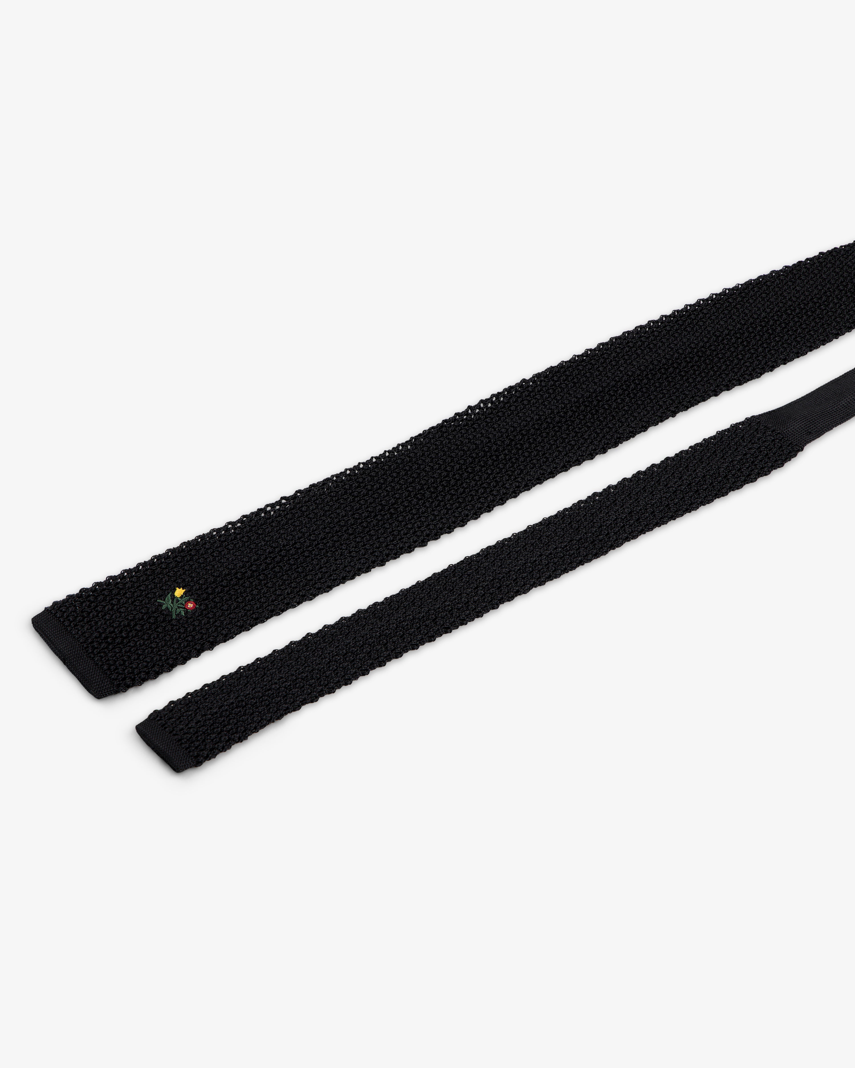 Crest Silk Knit Tie in black with small floral embroidery near the tip.