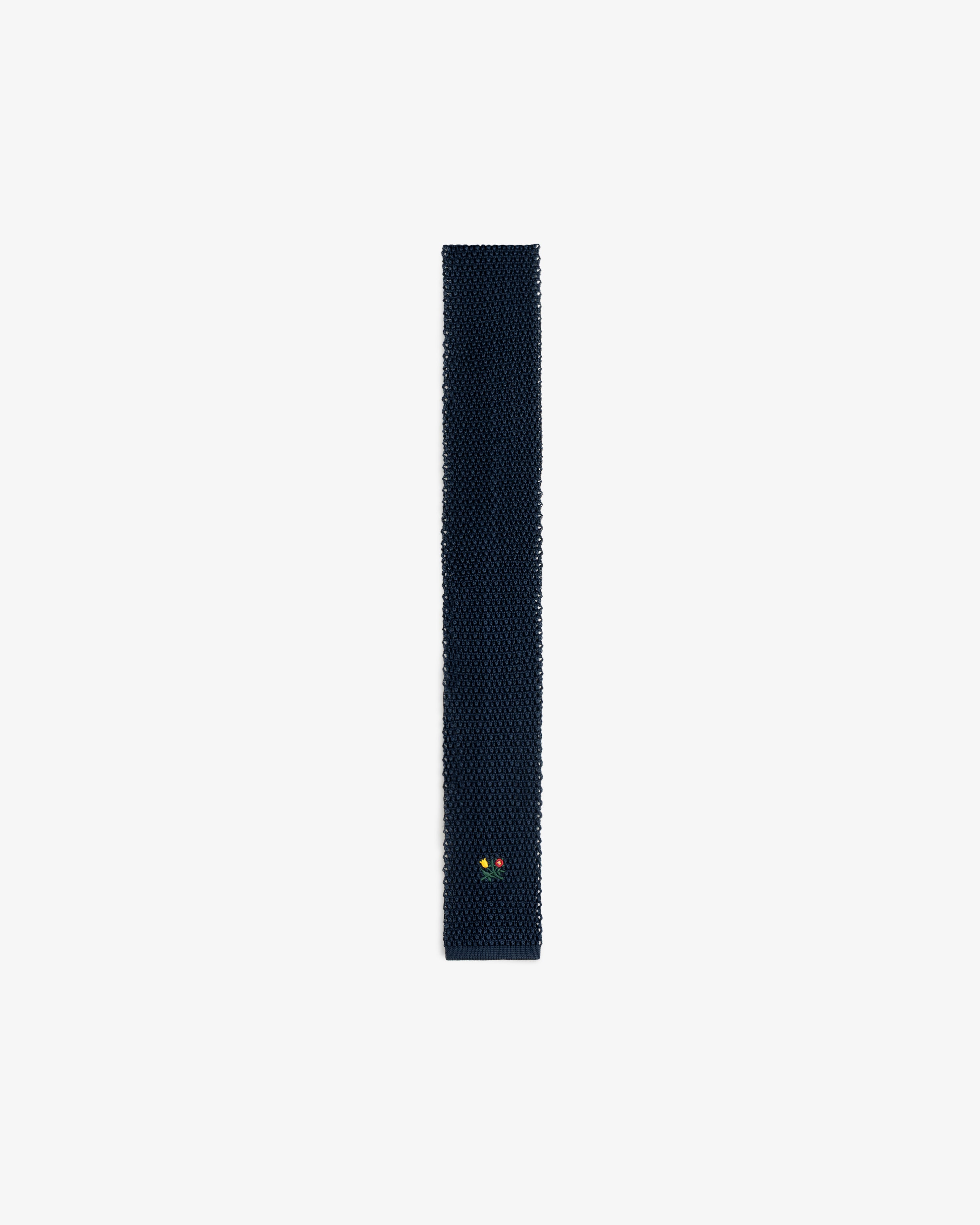 Dark navy Crest Silk Knit Tie with a small floral embroidery near the pointed tip.