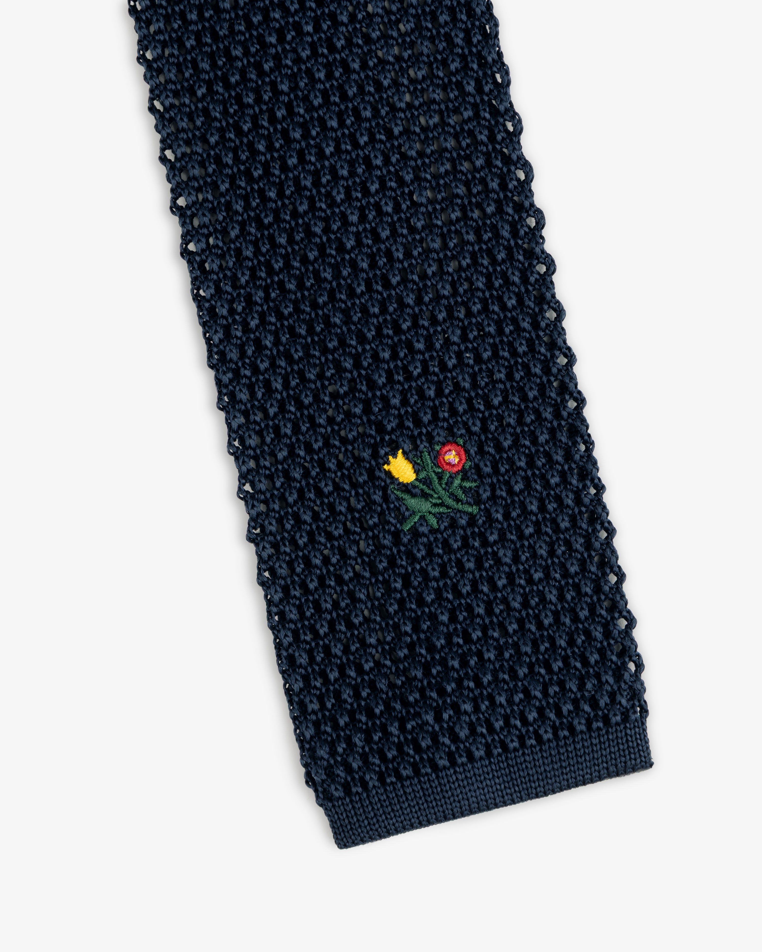 Crest Silk Knit Tie in navy blue, featuring a small embroidered floral motif.
