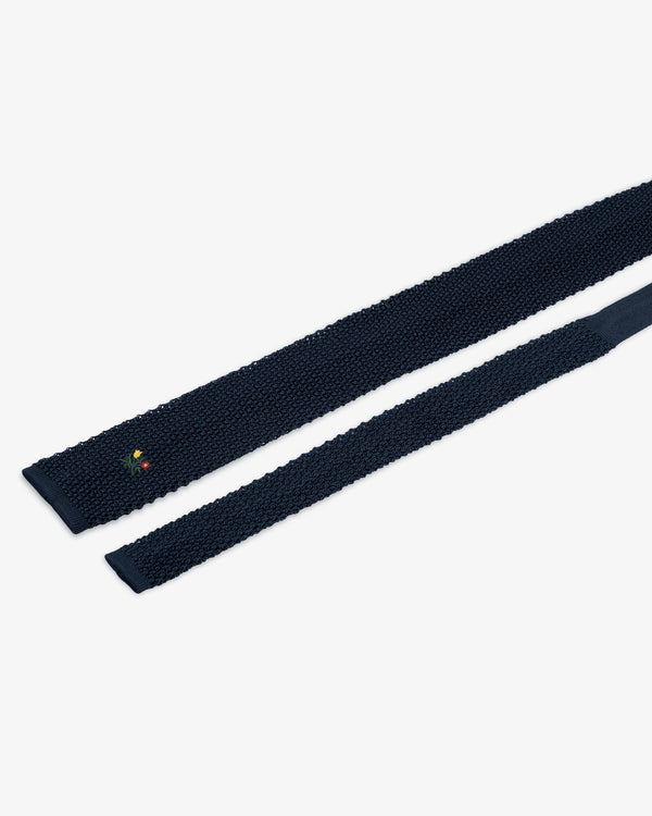 Crest Silk Knit Tie in navy blue with a small embroidered floral crest near the tip.