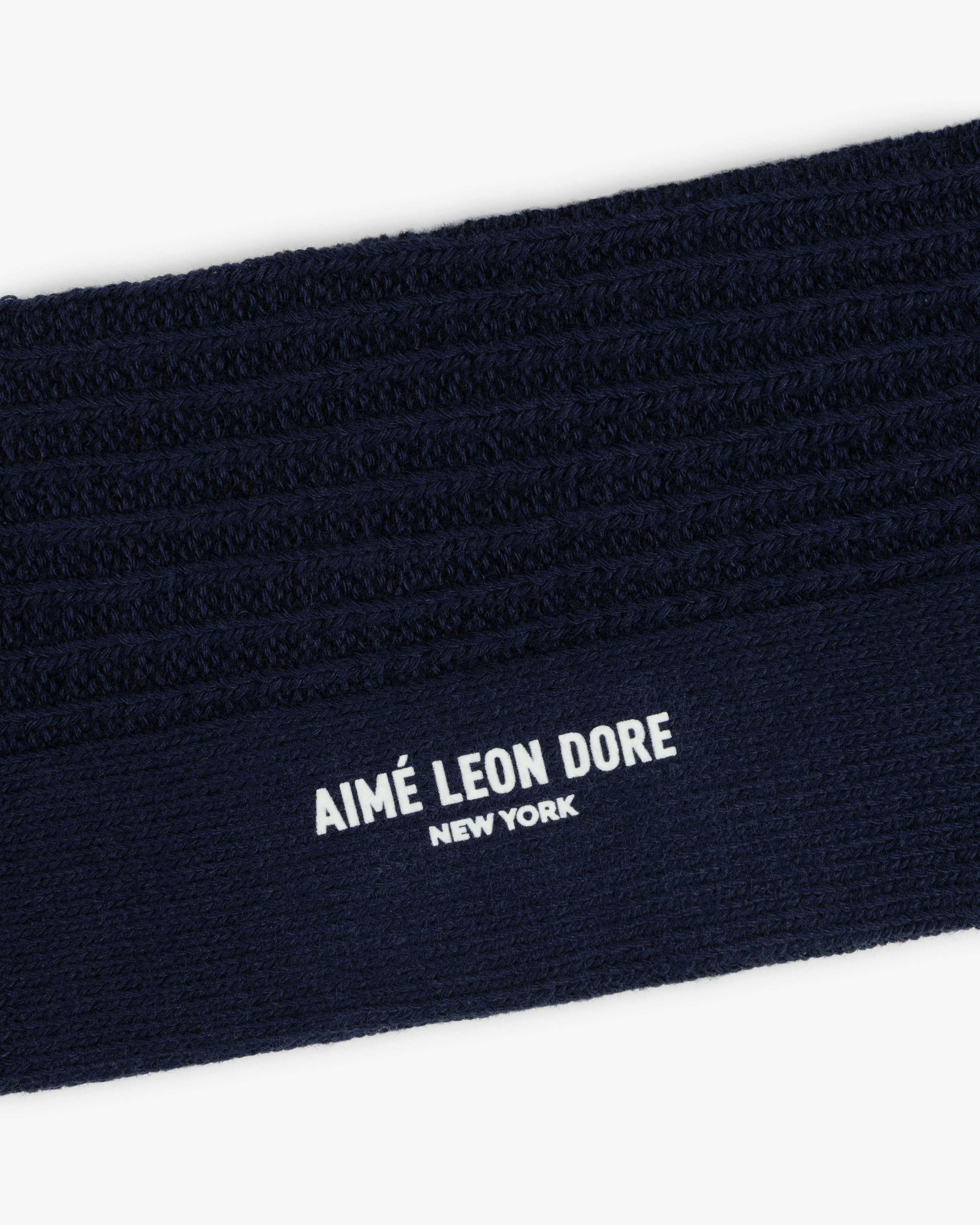 Dark navy blue ribbed cuff of a Cotton Waffle Sock with Aimé Leon Dore New York printed in white.