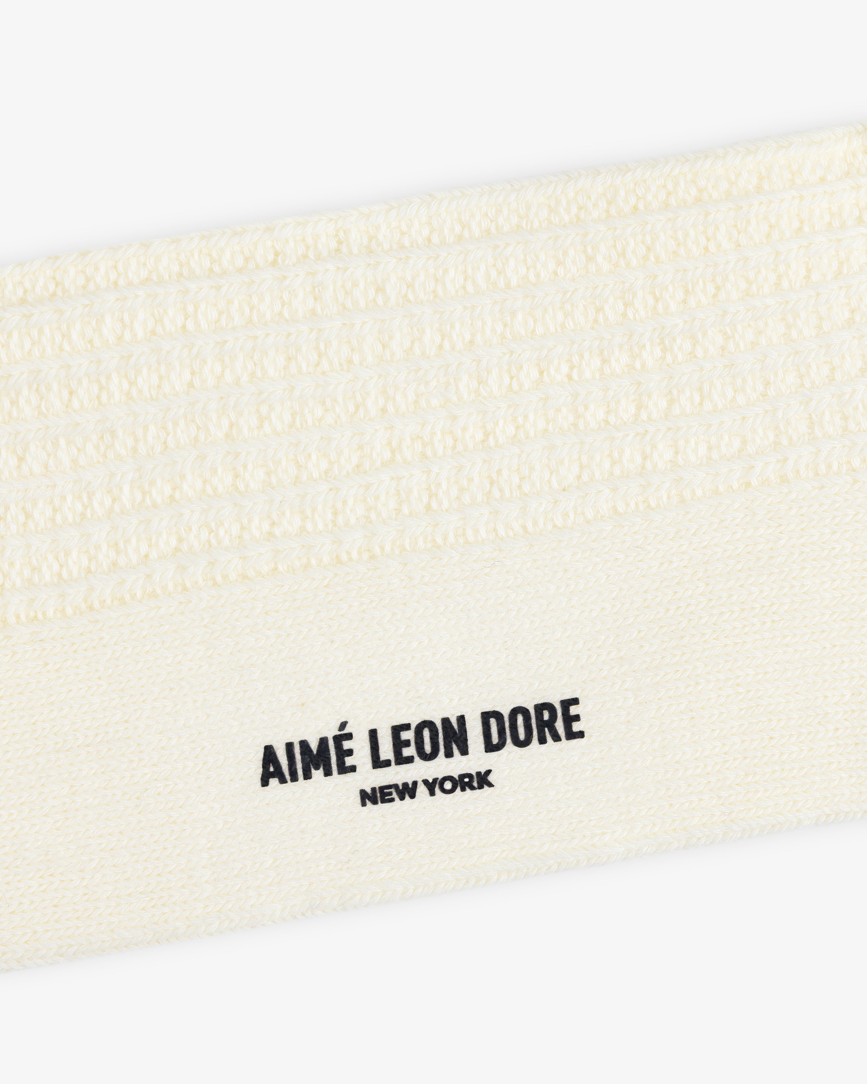 Close-up of a cream-colored textured Cotton Waffle Sock with Aimé Leon Dore New York printed in black.