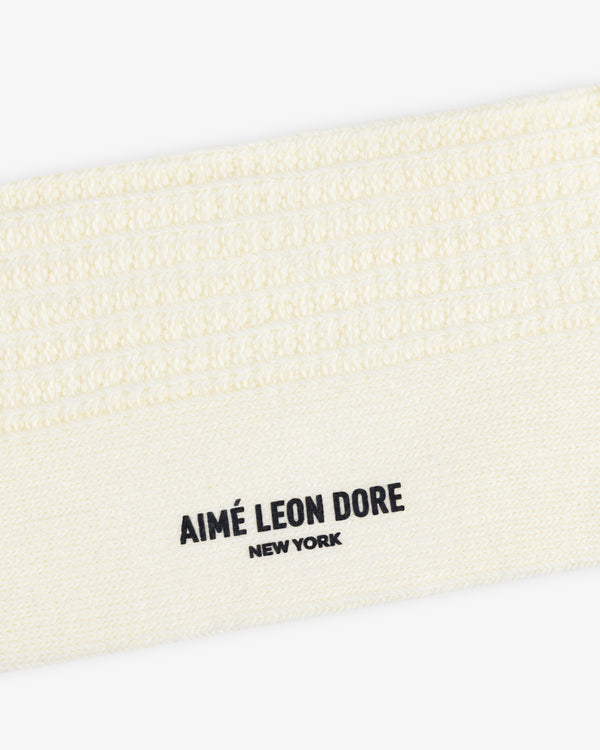 Close-up of a cream-colored textured Cotton Waffle Sock with Aimé Leon Dore New York printed in black.