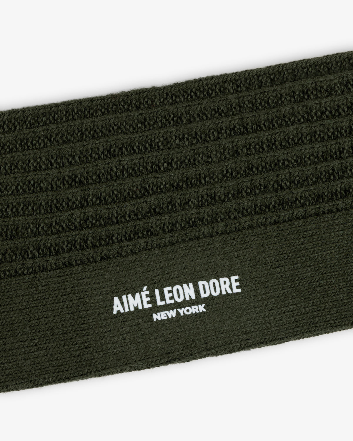 Close-up of a Cotton Waffle Sock in olive green with a ribbed cuff featuring the text AIMÉ LEON DORE NEW YORK.