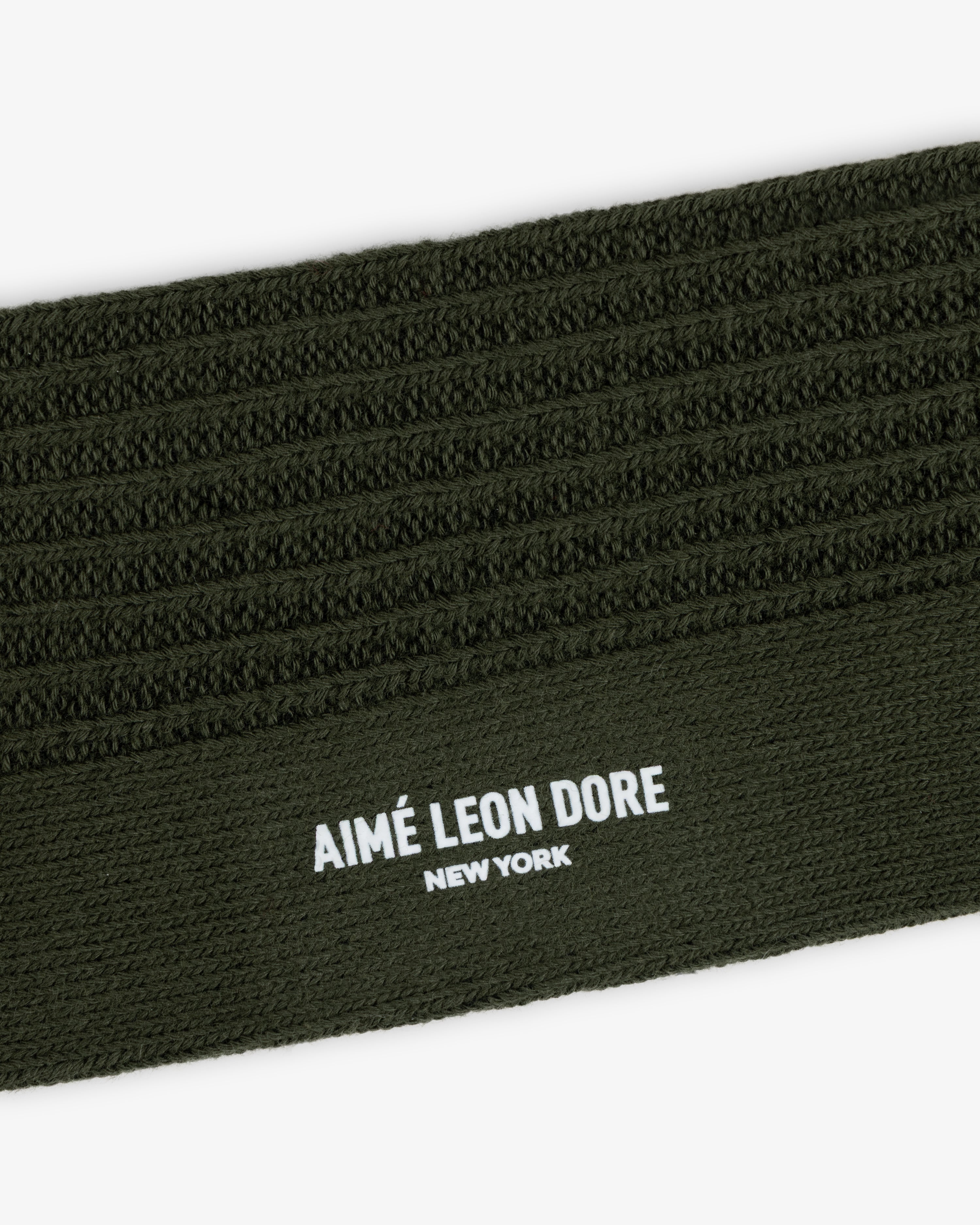 Close-up of a Cotton Waffle Sock in olive green with a ribbed cuff featuring the text AIMÉ LEON DORE NEW YORK.