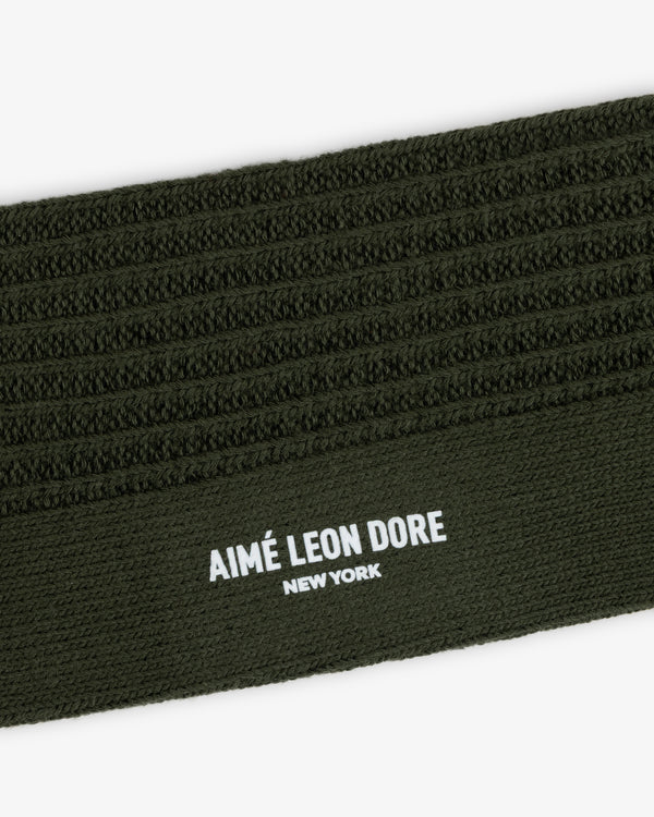Close-up of a Cotton Waffle Sock in olive green with a ribbed cuff featuring the text AIMÉ LEON DORE NEW YORK.