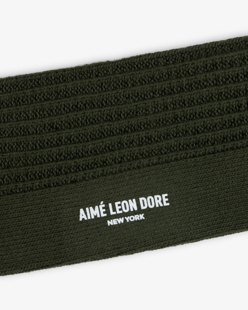 Close-up of a Cotton Waffle Sock in olive green with a ribbed cuff featuring the text AIMÉ LEON DORE NEW YORK.