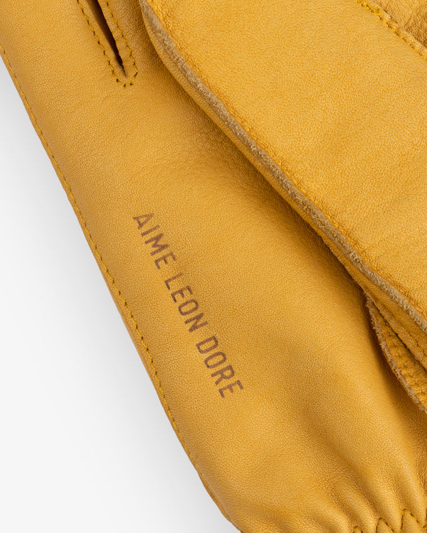 Mustard yellow Wakayama leather gloves featuring the brand name stamped on the cuff.
