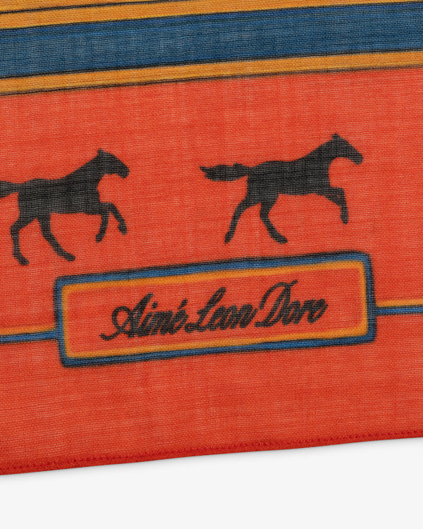 Bayard Silk Bandana: Red fabric with black horses and cursive Aimé Leon Dore text in an orange bordered rectangle.