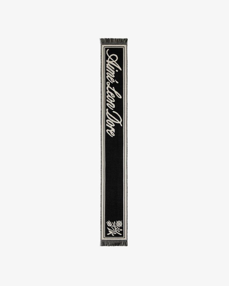 Wool Script Scarf in black with white script text, a floral emblem, and fringe at both ends.
